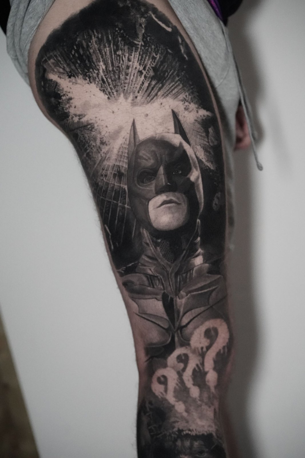 A black and white tattoo of batman on a person 's leg.